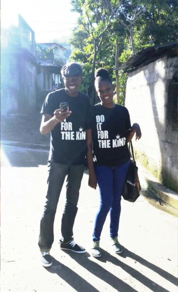 Two customers standing outdoors wearing black “Do It For The King” t-shirts, smiling together in a natural setting.