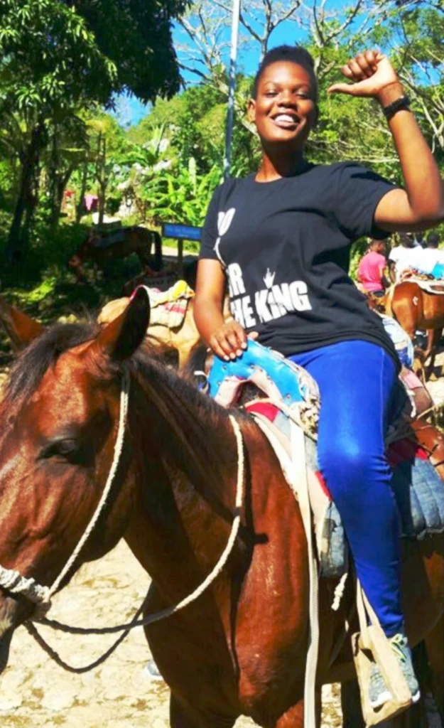 Customer riding a horse outdoors while wearing a black “Do It For The King” t-shirt, smiling in a natural setting.