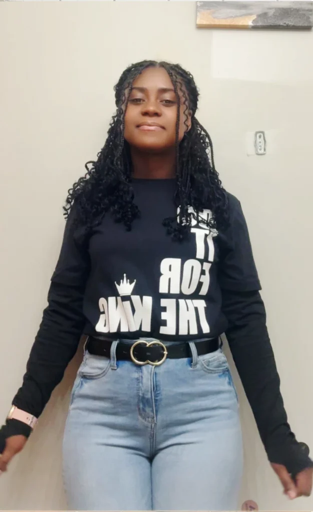 Customer wearing a black “Do It For The King” long sleeve shirt, standing confidently in a casual everyday outfit.